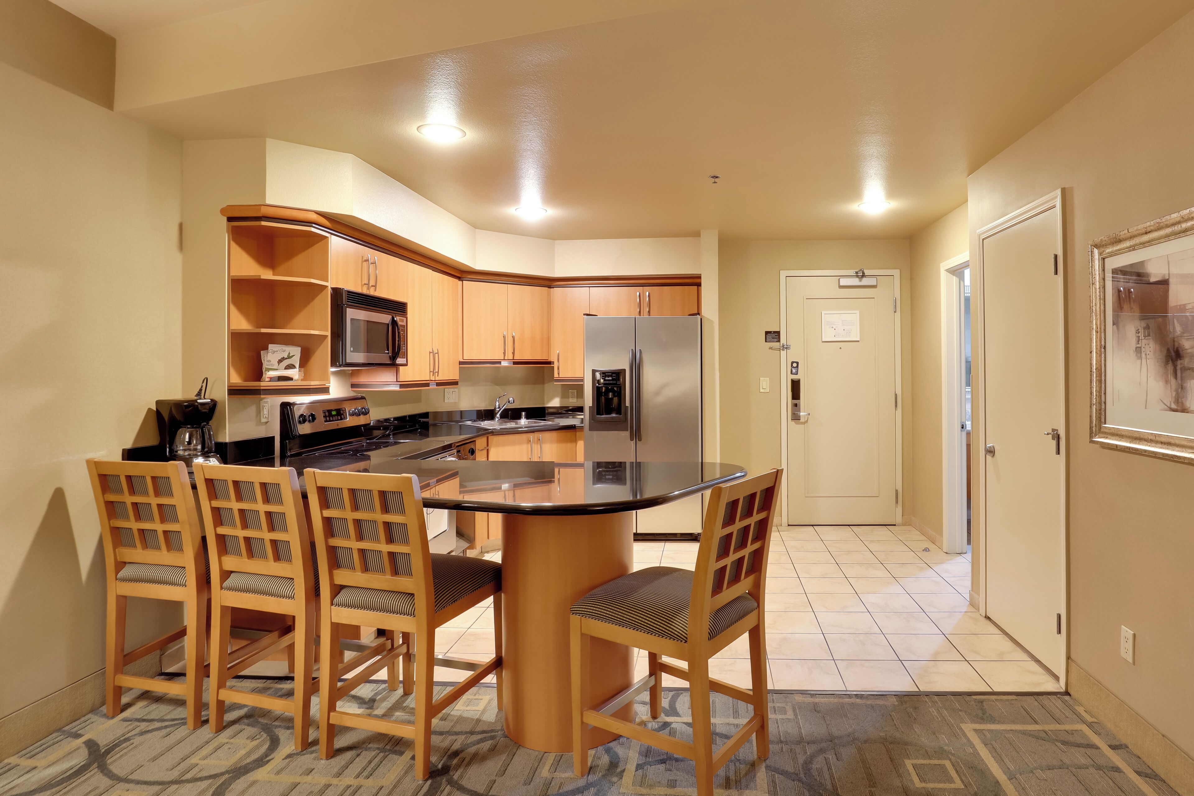 A compact kitchen with wooden cabinets, a central island, and a microwave.