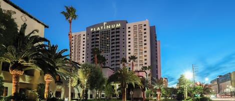 A high-rise hotel named 'Platinum' with a modern design, surrounded by palm trees and well-lit streets.