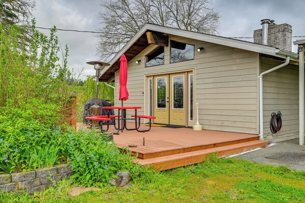 A wooden deck with picnic tables and a red umbrella, a door, and a chimney.