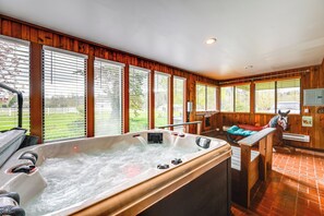 A hot tub with a wooden interior, large windows, and a horse statue.
