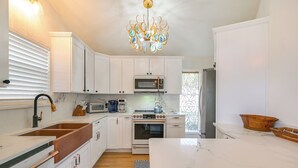 Eine moderne Küche mit weißen Schränken, einem Edelstahl-Kühlschrank, einem eingebauten Backofen und einer Mikrowelle.