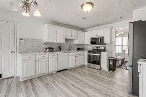 A modern kitchen with white cabinets, a microwave, stove, and a refrigerator.