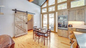 Una cucina con mobili in legno, un tavolo da pranzo e una porta a griglia scorrevole.