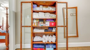 Une armoire en bois dotée de plusieurs étagères, dont certaines contiennent des serviettes pliées et d’autres articles.
