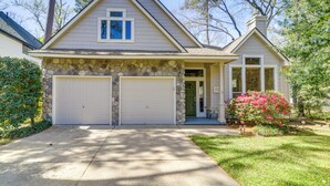 A two-story house with a stone facade, two garage doors, and a front porch. - Hot Tub, Fire Pit: Retreat in The Woodlands! (The Woodlands)
