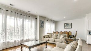A living room with a wooden coffee table, a beige sofa, and a glass-top table. - 7 Mi to The Galleria: Modern Home w/ Fenced Yard (Houston)