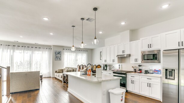 A modern kitchen with white cabinets, stainless steel appliances, and pendant lighting. - 7 Mi to The Galleria: Modern Home w/ Fenced Yard (Houston)