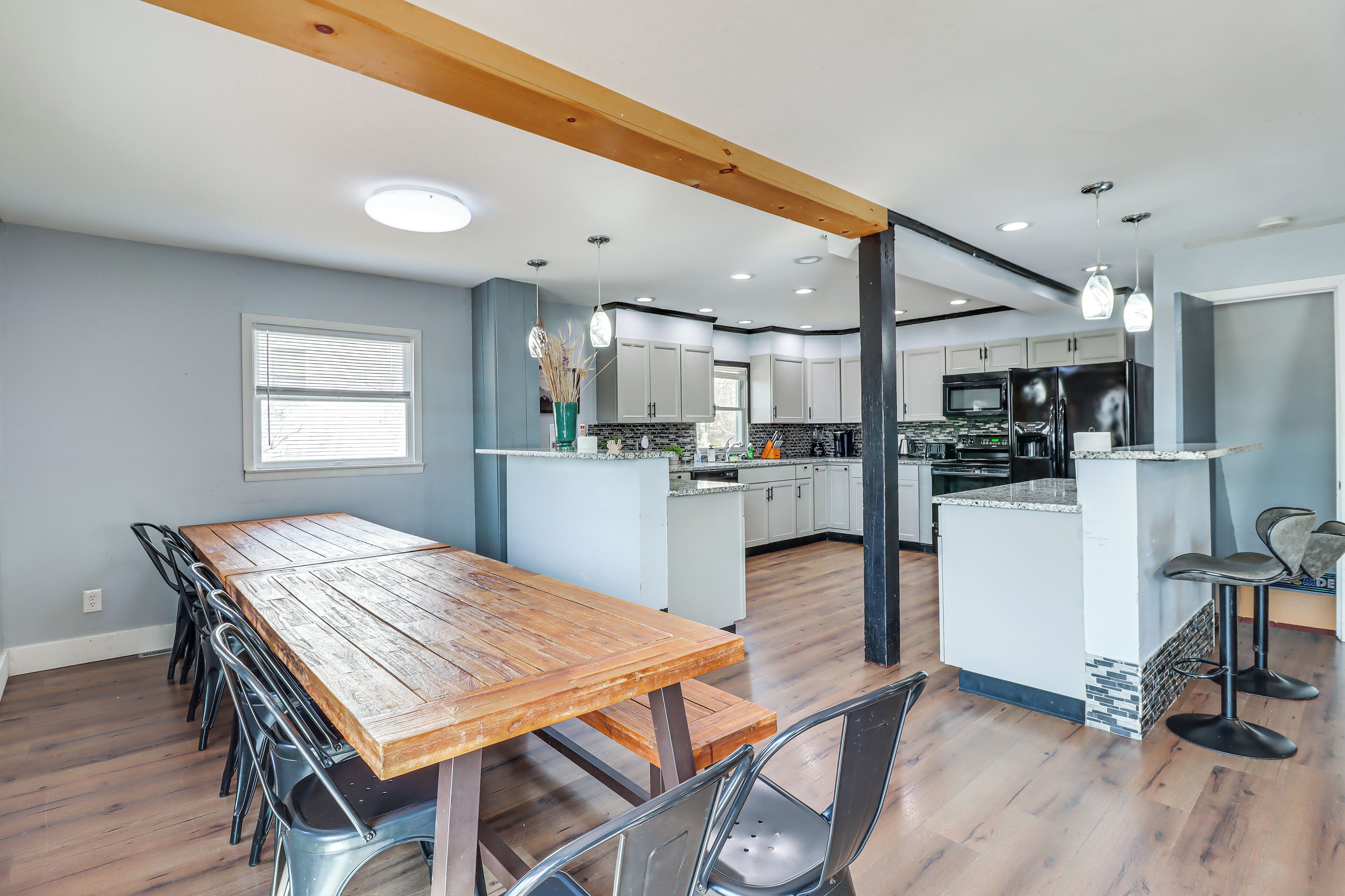 A spacious kitchen with a wooden dining table and bar stools, featuring modern appliances and a large island.