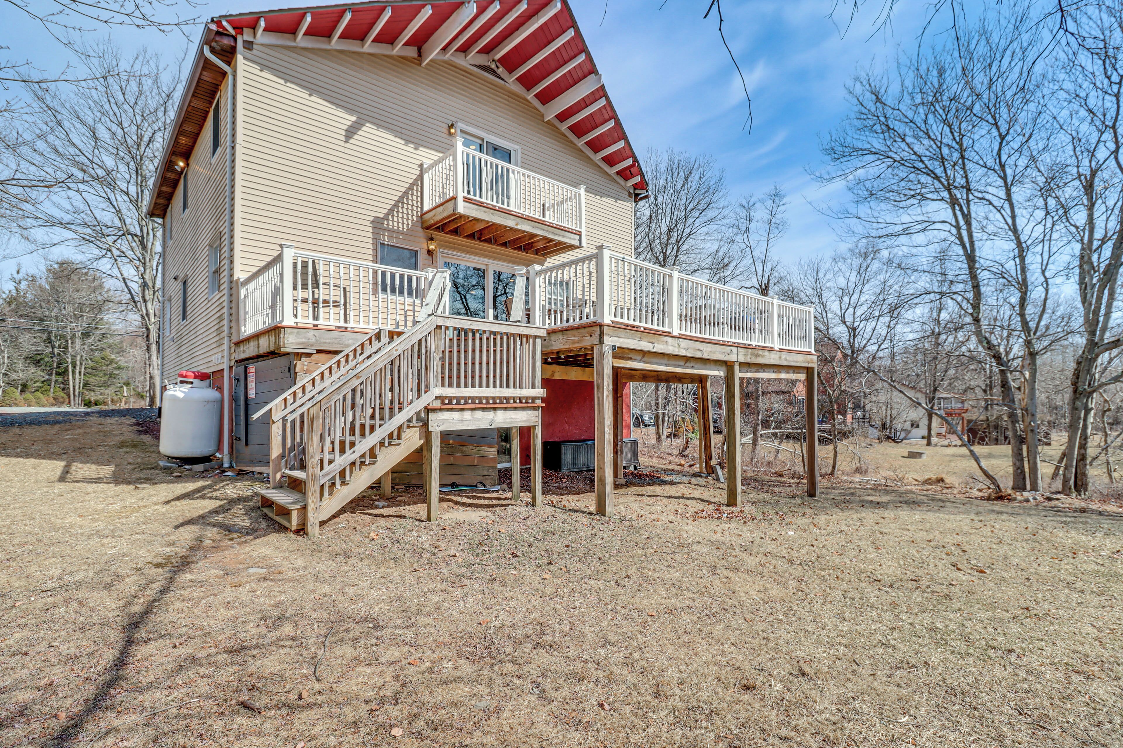 A two-story house with a wooden deck and a red roof.