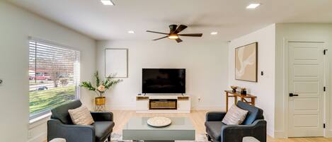 A modern living room with a flat-screen TV, two sofas, a coffee table, and a ceiling fan.