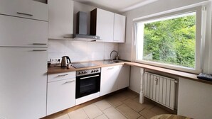 A modern kitchen with white cabinets, a wooden countertop, a stove, and a window with a view of greenery.