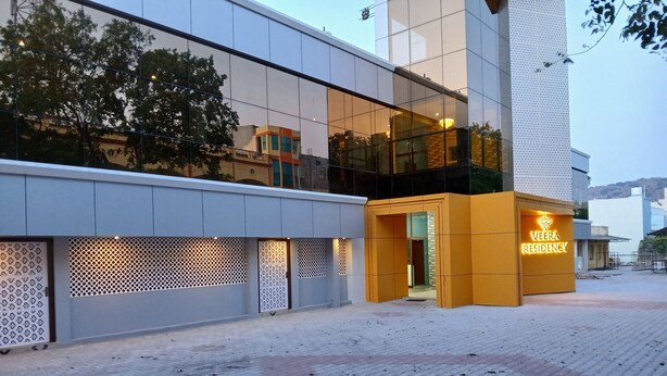 A modern building with a glass facade and a yellow entrance labeled "Veera Residency." - Veera Residency (Gingee)