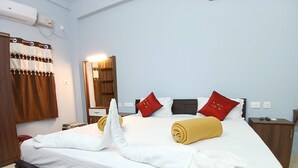 A hotel room with a neatly made bed, a wooden headboard, a mirror, a nightstand with a phone, and a wall-mounted air conditioner. - Veera Residency (Gingee)