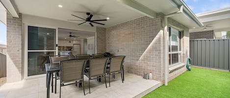 A patio with a table and chairs, a ceiling fan, and a view of the backyard.