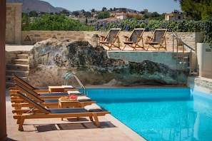 Un espace piscine avec des chaises longues et un mur en pierre.