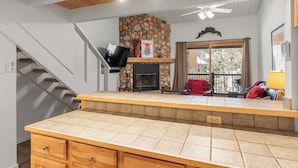 A kitchen with a stone fireplace, wooden cabinets, and a tiled countertop. - Cozy Top Floor Unit, Near Main St. Hot tubs & Pool (Breckenridge)