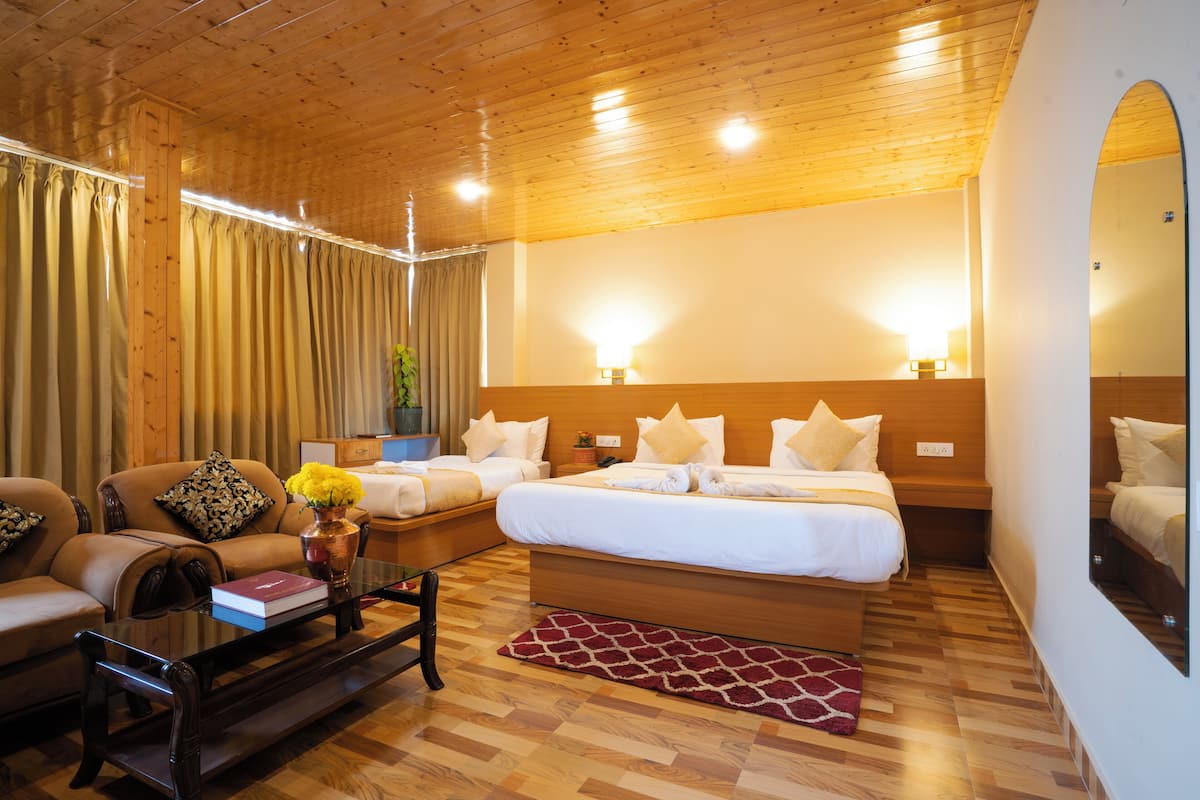 Ein Hotelzimmer mit Holzboden, zwei Betten, einer Couch, einem Couchtisch und einem Spiegel.