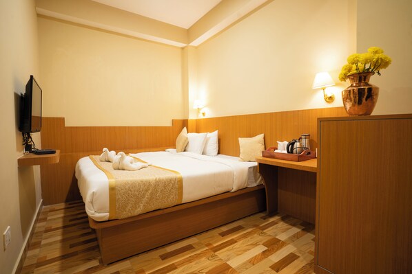 A hotel room with a bed, bedside table, lamp, and a vase with flowers. - Sikkim Bliss (Gangtok)