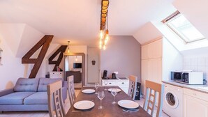Een ruimtelijk ingerichte leefruimte met een eethoek, kitchenette en een slaapbank.
