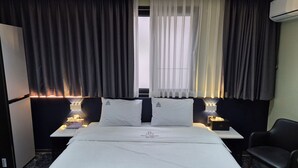 Une chambre d’hôtel avec un lit, deux tables de chevet, une chaise et des rideaux.