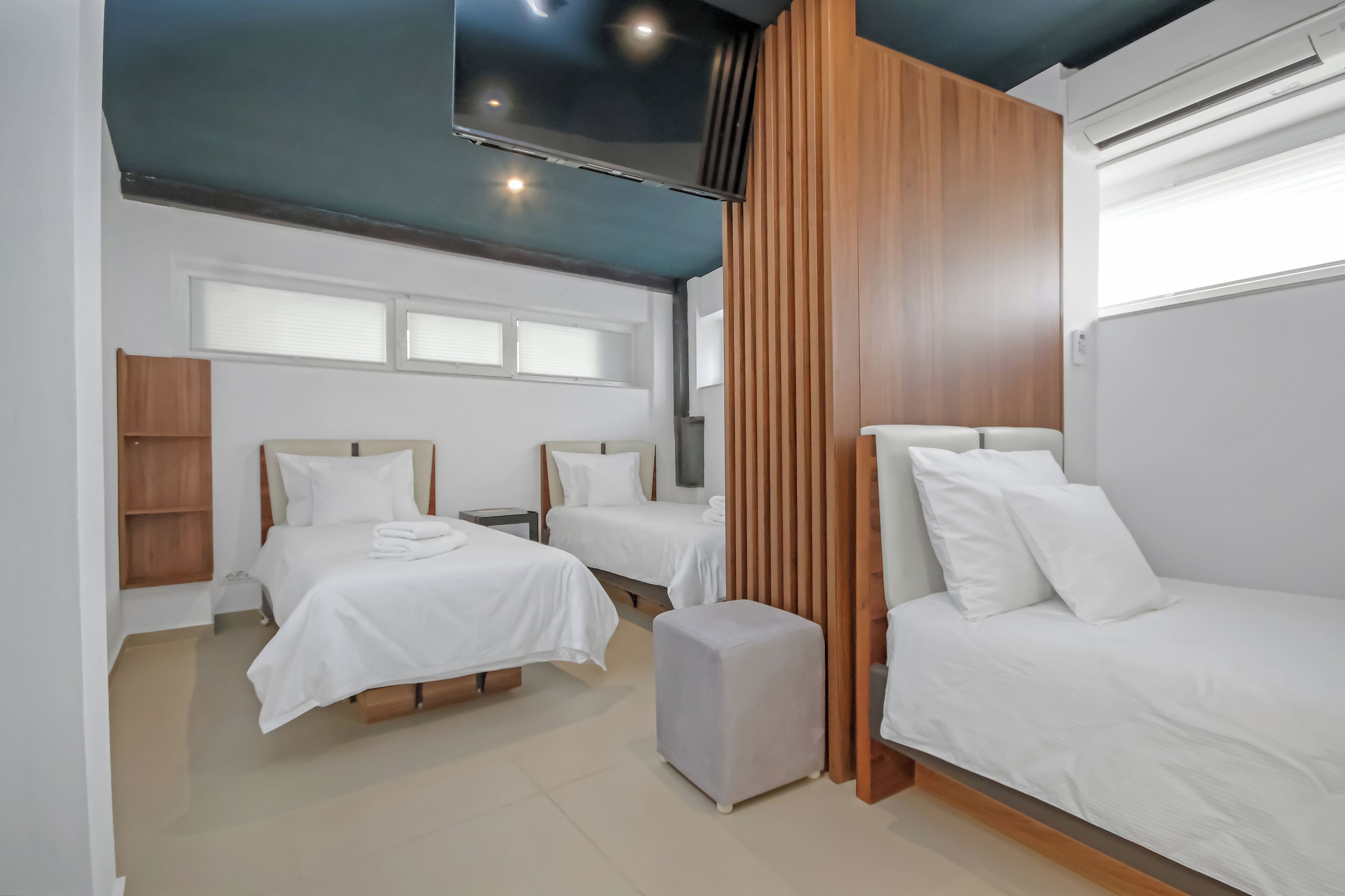 A modern hotel room with two beds, a TV, and a wooden panel wall.