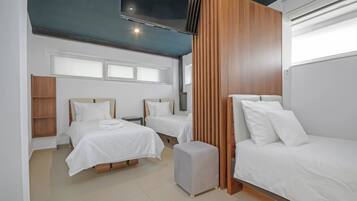 A modern hotel room with two beds, a TV, and a wooden panel wall.