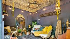 Une pièce chaleureuse avec un plafond en osier, des meubles en rotin et un miroir doté d’un cadre décoratif.