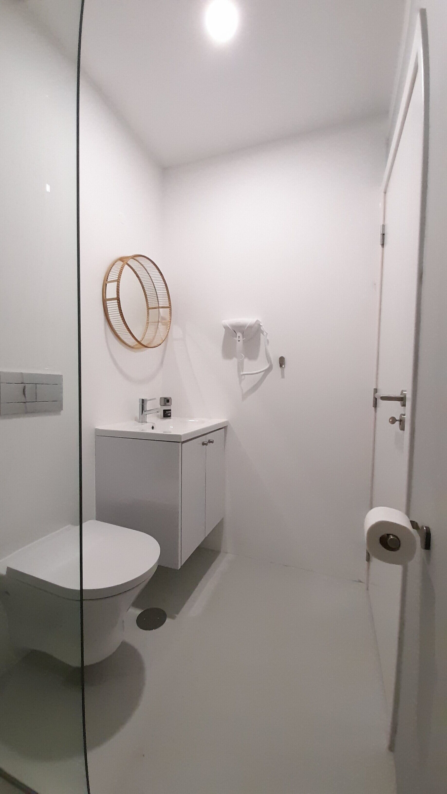 Een kleine, witte badkamer met toilet, wastafel en spiegel.