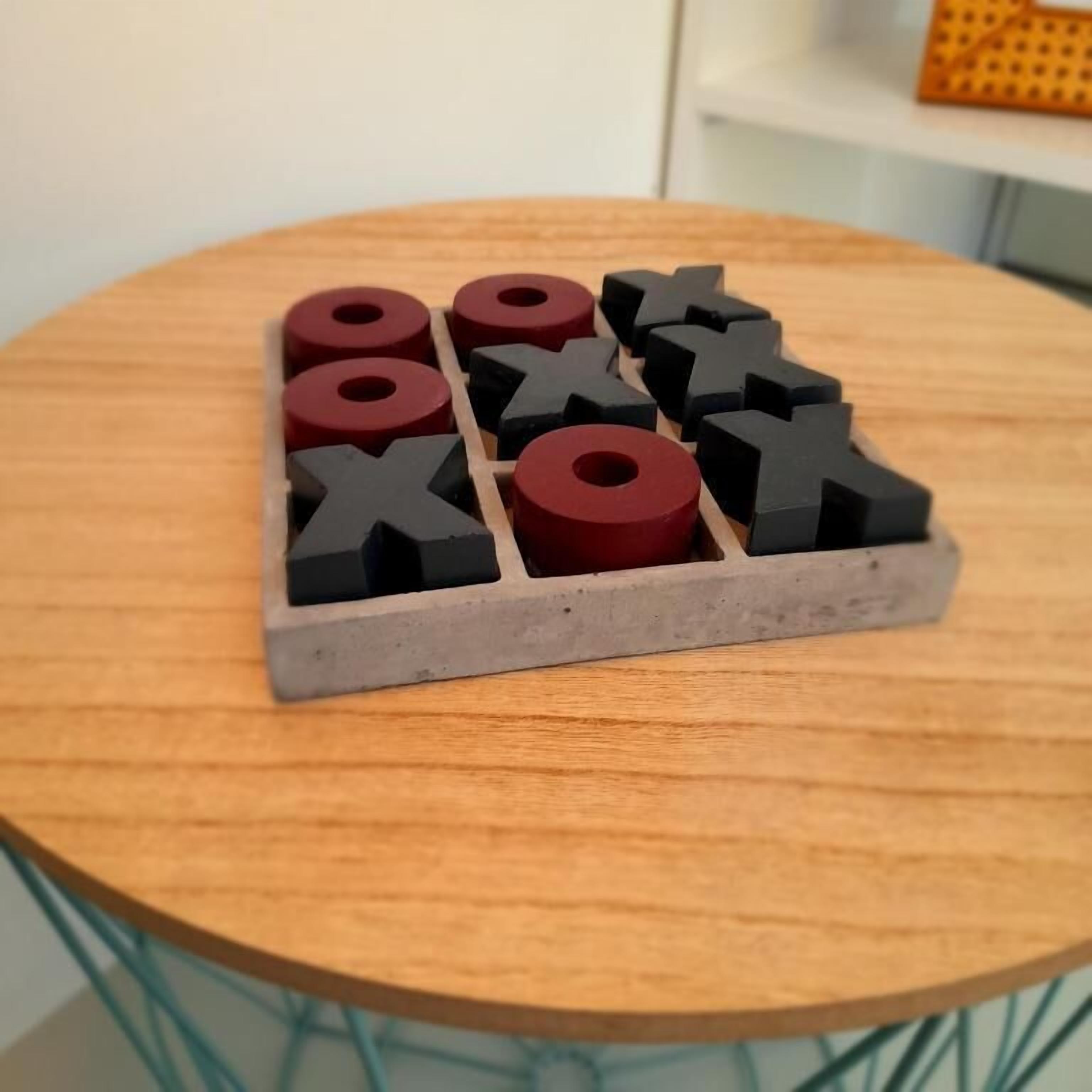 Una mesa de madera con una bandeja de concreto que contiene fichas de juego negras y rojas.