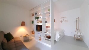 Een moderne woonkamer met een bank, een salontafel en een wit kastenmeubel met diverse spullen.