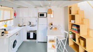 Een kleine keuken met een wasmachine, magnetron en een eethoek met een tafel en stoelen.