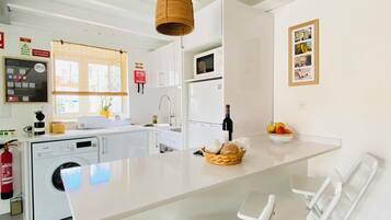 A modern kitchen with a central island, a washing machine, a microwave, and a sink.