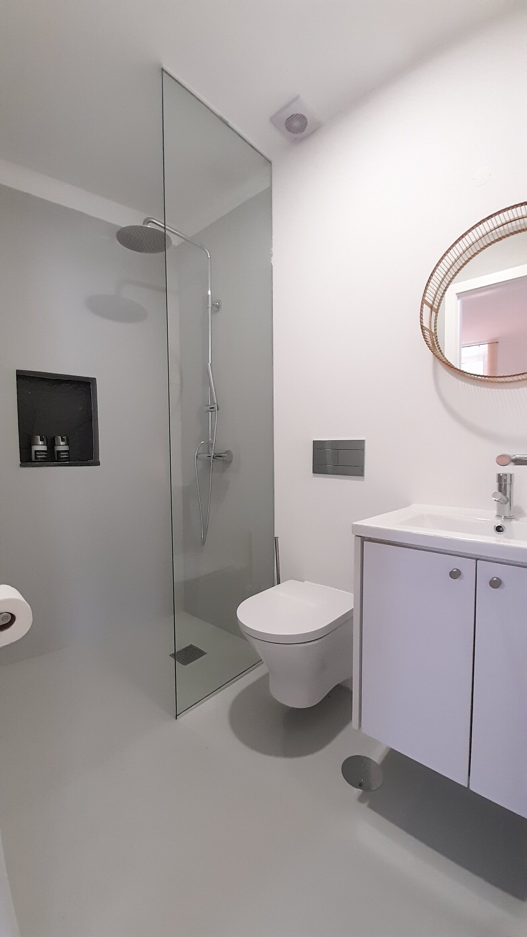 A modern bathroom with a glass-enclosed shower, a toilet, and a vanity with a mirror.
