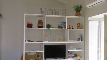 A living room with a white bookshelf, a television, and a brown sofa.