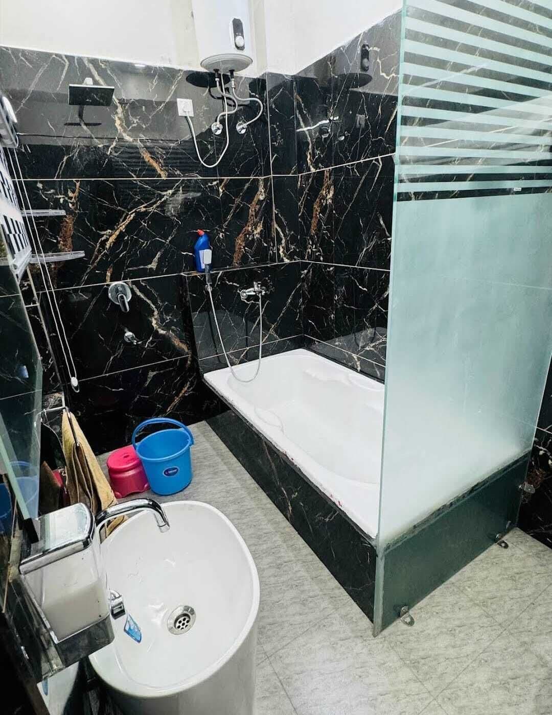 A bathroom with a bathtub, a sink, and a shower. There are two buckets and a towel rack.