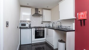 A compact kitchen with white cabinets, a microwave, a toaster, and a sink. - 1 Bedroom Twin Apartment (Newcastle-upon-Tyne)