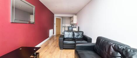 Una sala de estar moderna con un sofá de cuero negro, una mesa de centro de madera y una pared de acento roja.