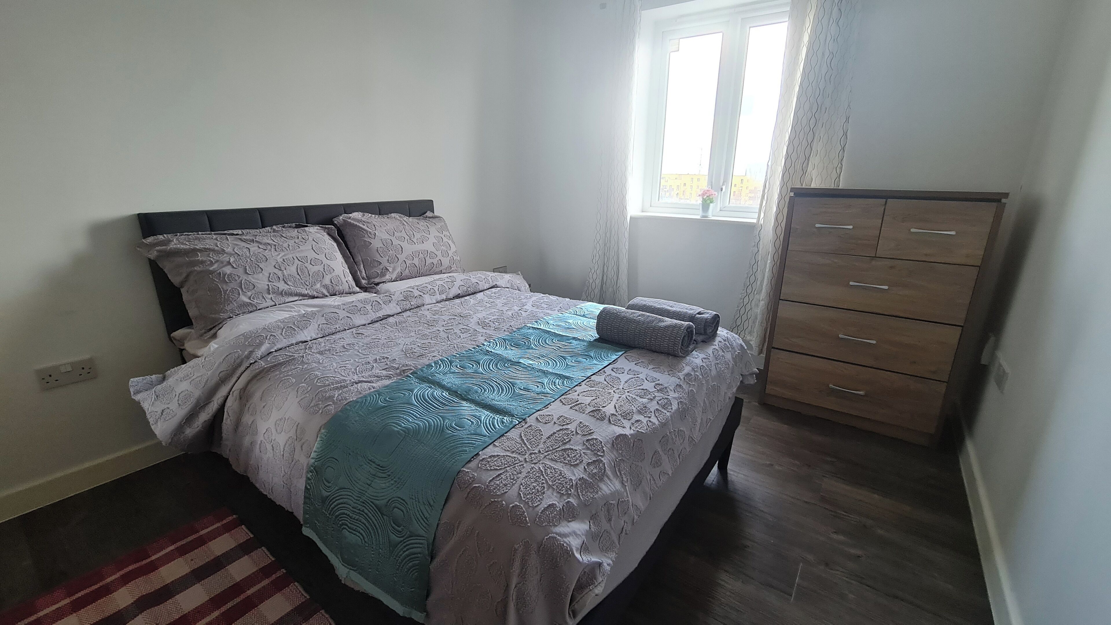 Une chambre à coucher avec un lit, une commode et une fenêtre.