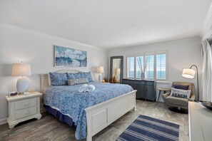 A bedroom with a bed, nightstands, a dresser, a chair, and a window with blinds.