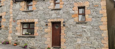 Ein Steinhaus mit Holztür, Fenstern und Blumentöpfen.