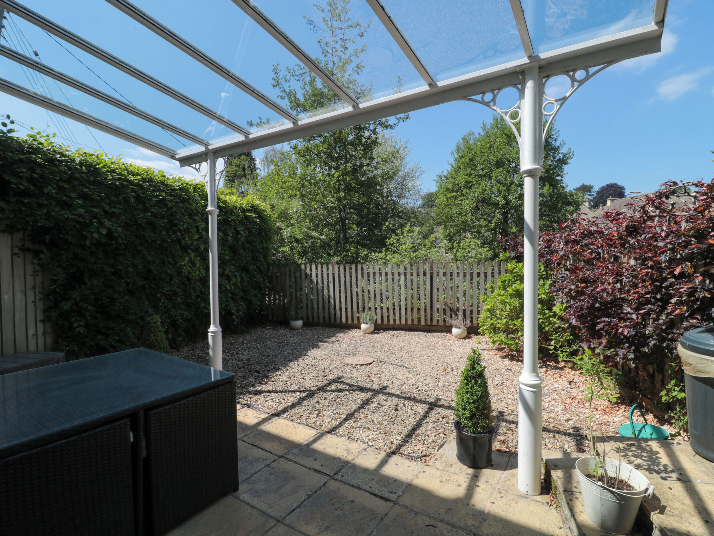 Ein überdachter Patio-Bereich mit einer Pergola, Sitzgelegenheiten und Kübelpflanzen.