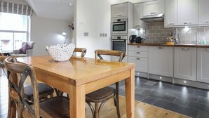 Une cuisine moderne avec des meubles blancs, une table à manger en bois et une fenêtre offrant une belle vue.