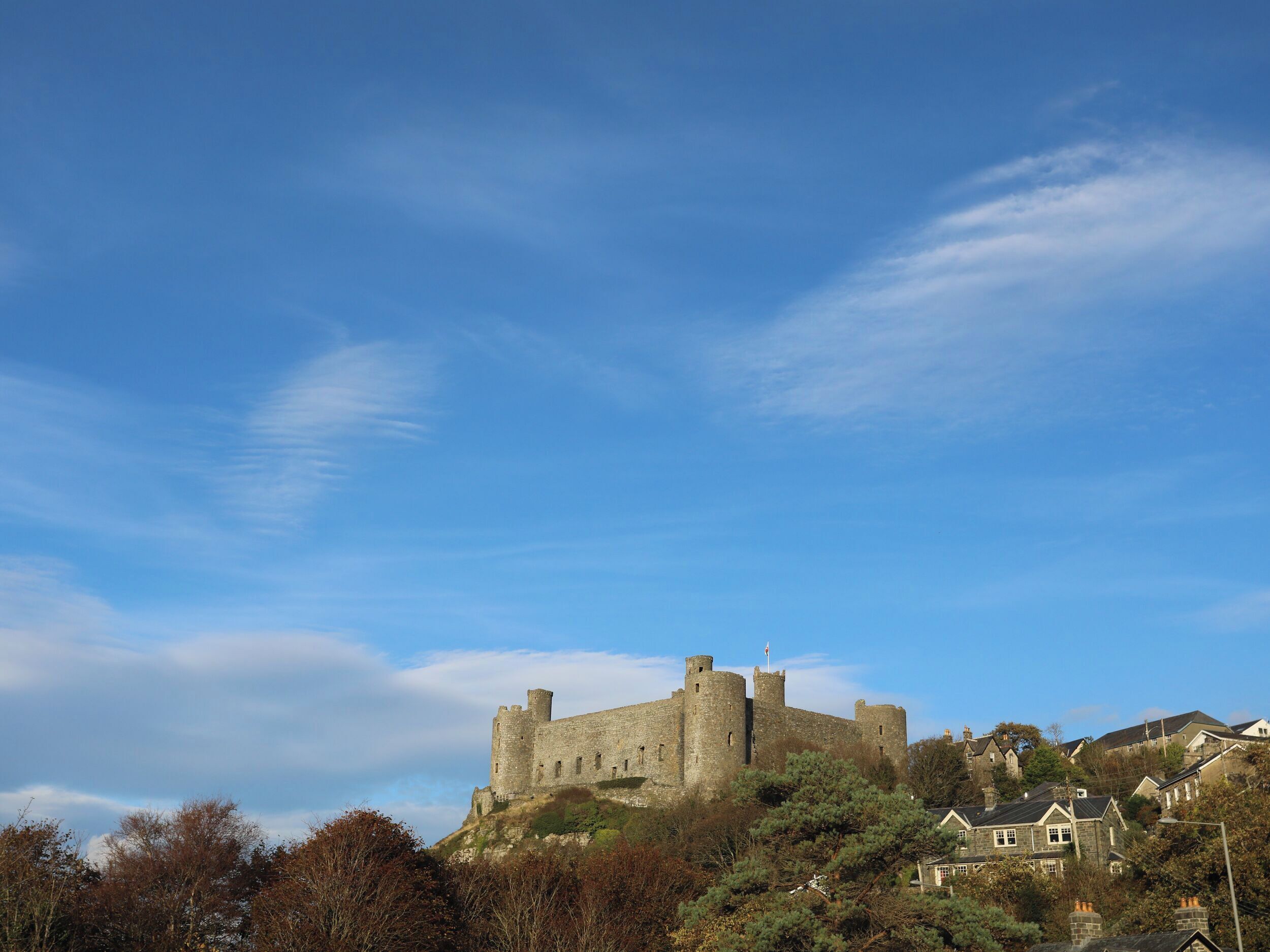 A historic stone castle on a hill with a clear sky.