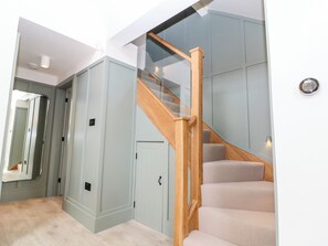 A modern interior with a wooden staircase, light-colored walls, and a mirror. - 12 Manor Farm Close (Chipping Norton)