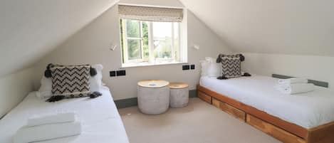 Une chambre avec deux lits, une fenêtre et deux petites tables rondes.