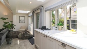A modern kitchen with a skylight, a dining area with a sofa, and a view of the outside. - 12 Manor Farm Close (Chipping Norton)