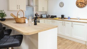 A kitchen with white cabinets, a wooden countertop, a brick ceiling, and a wall clock. - The Clockhouse (Montgomery)