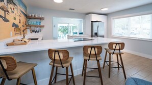 A modern kitchen with a large island, bar stools, and a view of the outdoors. - 3BR/2BA Luke's Landing Island Home - Jensen Beach Retreat (Jensen Beach)