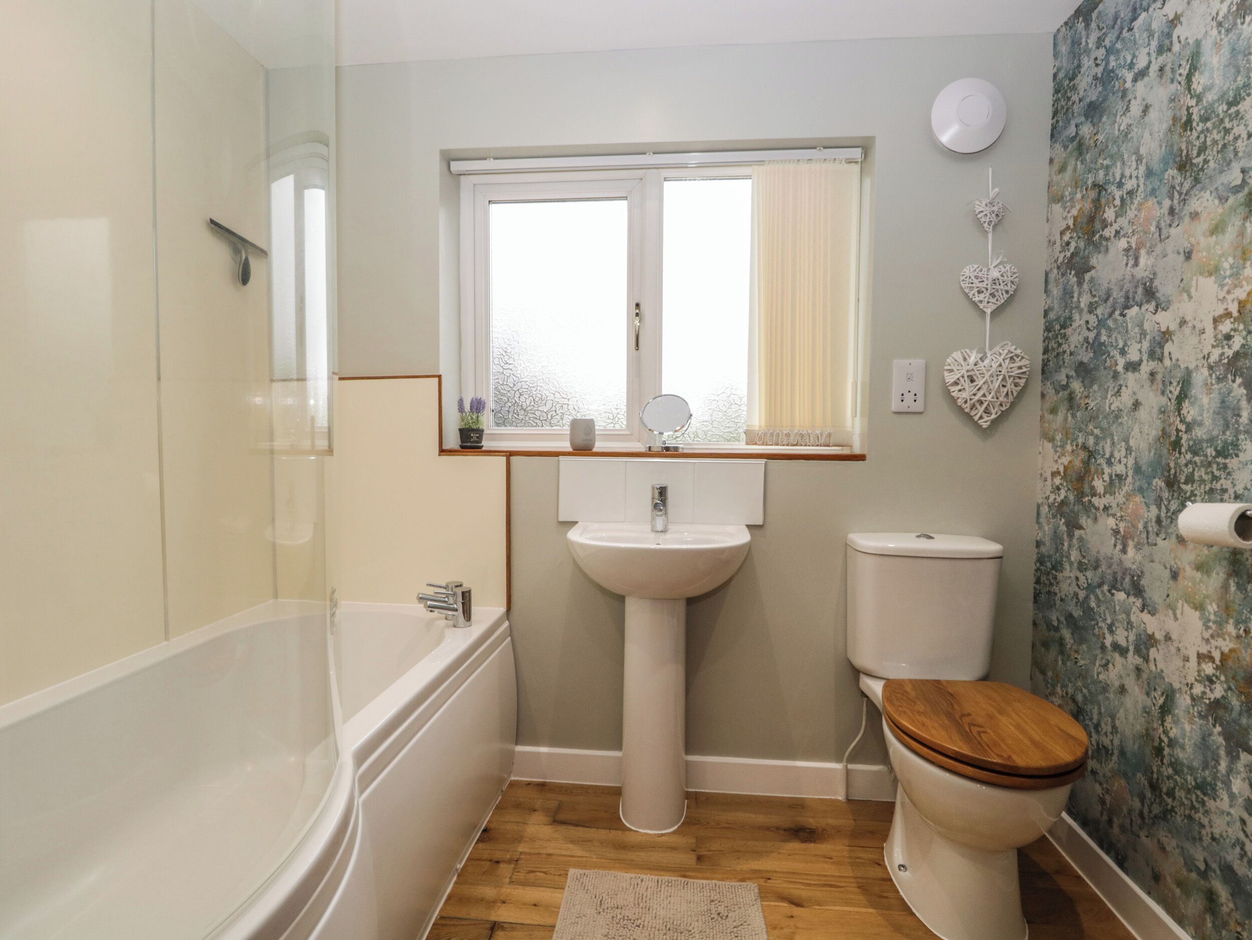 A bathroom with a bathtub, a sink, a toilet, and a window with a view.