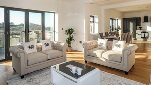 Amplia sala de estar con dos sofás, una mesa de centro y vistas a un comedor.
